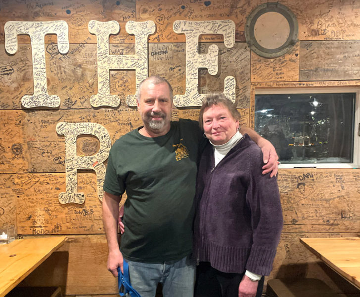 Steve and Karen Brackett, proprietors of King Ro Market and The Ro in Round Pond, stand in front of a wall in the pub autographed by hundreds of patrons. The couple said they are touched and appreciative of the all support they have been received since Steve's diagnosis with amyotrophic lateral sclerosis, or ALS, in August 2025. Fundraising efforts have raised more than $50,000 to date. (Sherwood Olin photo)