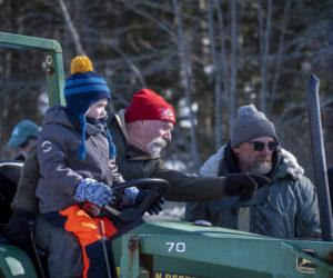 Thompson Ice House Preservation Corp. President Ken Lincoln gives directions from the seat of a tractor while his grandson Sam, 5, looks on during the annual ice harvest in South Bristol on Sunday, Feb. 15. (Jessica Rivers photo)