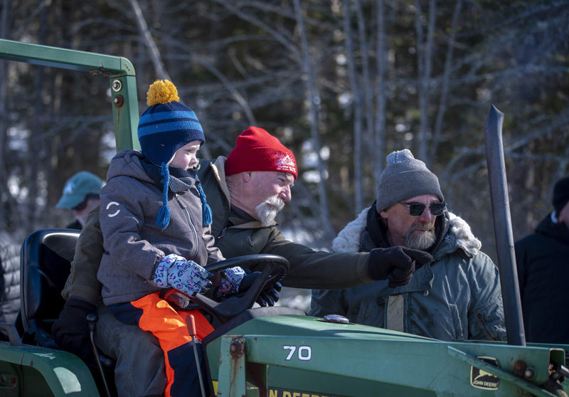 Thompson Ice House Preservation Corp. President Ken Lincoln gives directions from the seat of a tractor while his grandson Sam, 5, looks on during the annual ice harvest in South Bristol on Sunday, Feb. 15. (Jessica Rivers photo)