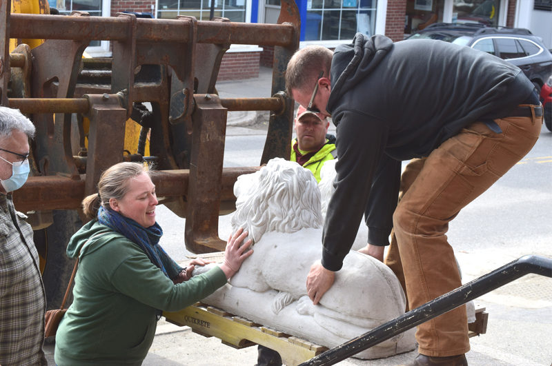 Torie DeLisle helps to move a cement lion onto a pedestal outside of Skidompha Library on Friday, March 13. The lions were installed on the 121st anniversary of the library's incorporation to honor the former executive director, Pam Gormley, who passed away in January of this year. (Christina Brown photo)