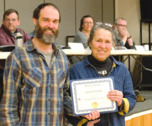 Whitefield Planning Board chair Jennifer Grady smiles next to select board chair Seth Bolduc after being awarded the Spirit of America Award for 2026. Recipients of the award are honored for their dedication to the community. In the background, from left, select board members Brent Hallowell, Erin Anderson, and Brian O'Mahoney look on. (Emily Bracher photo)