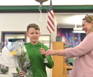 Lincoln County Spelling Bee moderator Jen Wright presents Great Salt Bay Community School eighth grader Otis Ball with a balloon and flowers after he won the county spelling bee. (Paula Roberts photo)