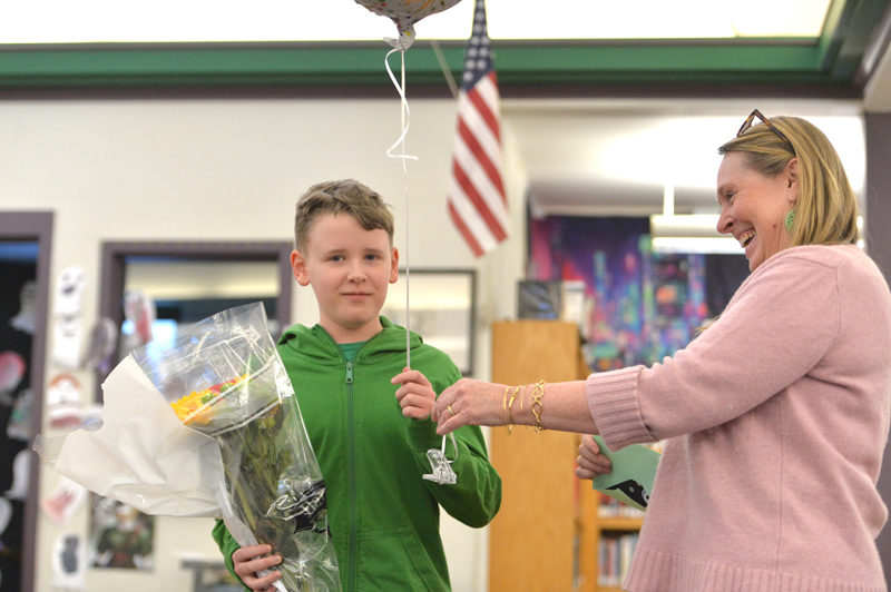Lincoln County Spelling Bee moderator Jen Wright presents Great Salt Bay Community School eighth grader Otis Ball with a balloon and flowers after he won the county spelling bee. (Paula Roberts photo)