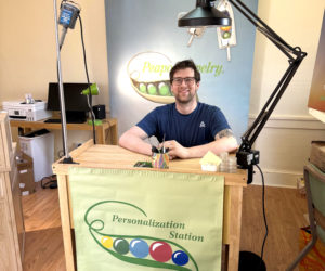 Joseph Lugosch, owner of Peadpod Jewelry, sits at the personalization station inside the stores second location at 202 Main St. in Damariscotta. The store is set to open Friday, May 1. (Photo courtesy Joseph Lugosch)