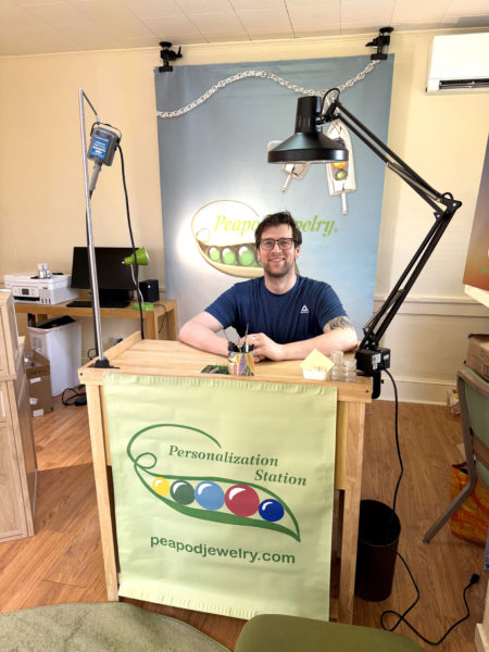 Joseph Lugosch, owner of Peadpod Jewelry, sits at the personalization station inside the stores second location at 202 Main St. in Damariscotta. The store is set to open Friday, May 1. (Photo courtesy Joseph Lugosch)