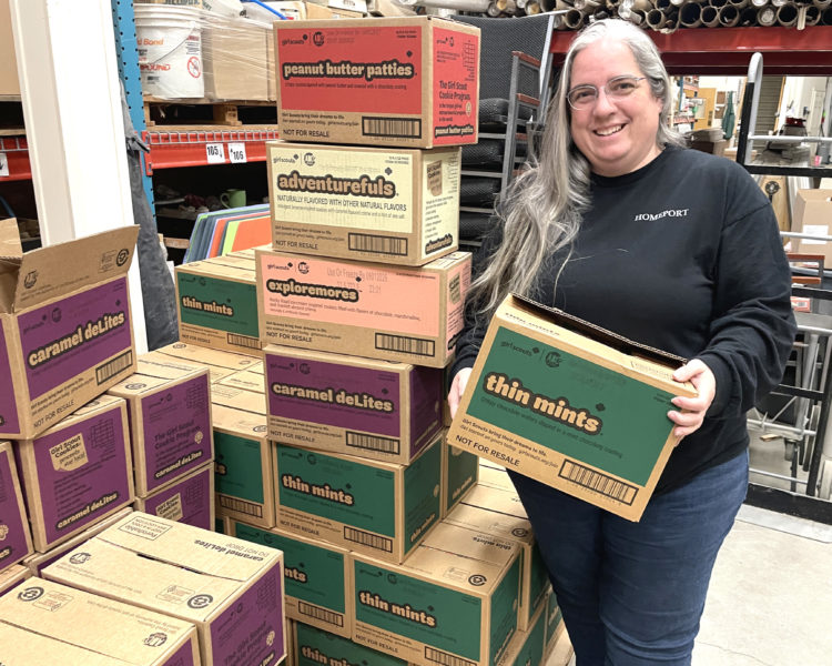 Angela White stands next to a stash of Girl Scout cookies at Homeport Supply in Newcastle. White first got involved with the Girl Scouts when her daughter Lucy took an interest. Fourteen years later, mother and daughter are both Lifetime Girl Scouts and Angela White said she has no plans to stop working with the organization. (Sherwood Olin photo)