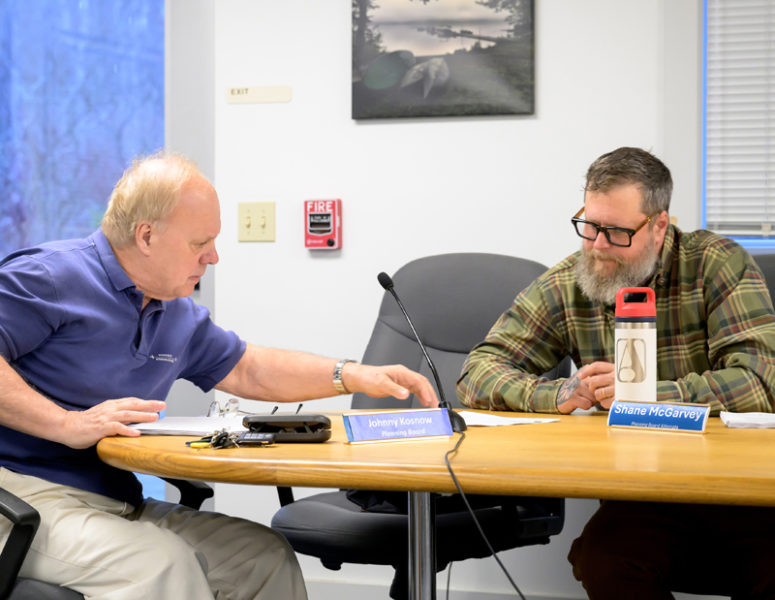 Waldoboro Planning Board members Johnny Kosnow (left) and Shane McGarvey review plans for the construction and installation of a building and biomass boiler to replace the current heating system at Medomak Valley High School. The project was approved with several conditions. (Bisi Cameron Yee photo)
