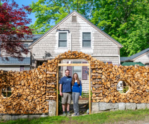 Will Fearn and Lauren Fowler stand in the arch that marks the entrance to their property in Damariscotta Mills on Wednesday, June 3. The couple built the surrounding wall out of the four cords of firewood that will be used to heat their home. (Bisi Cameron Yee photo)