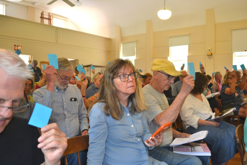 Westport Island voters raise their cards to approve an article at the annual town meeting on Saturday, June 20. (Charlotte Boynton photo)