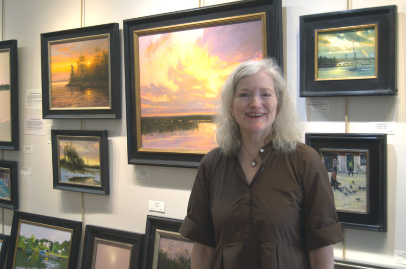 Sylvan Gallery director Ann Scanlan stands in front of some of the works in her Wiscasset gallery on Tuesday, June 30. The gallery is celebrating its 25th anniversary this year. (Lily Wasserman photo)